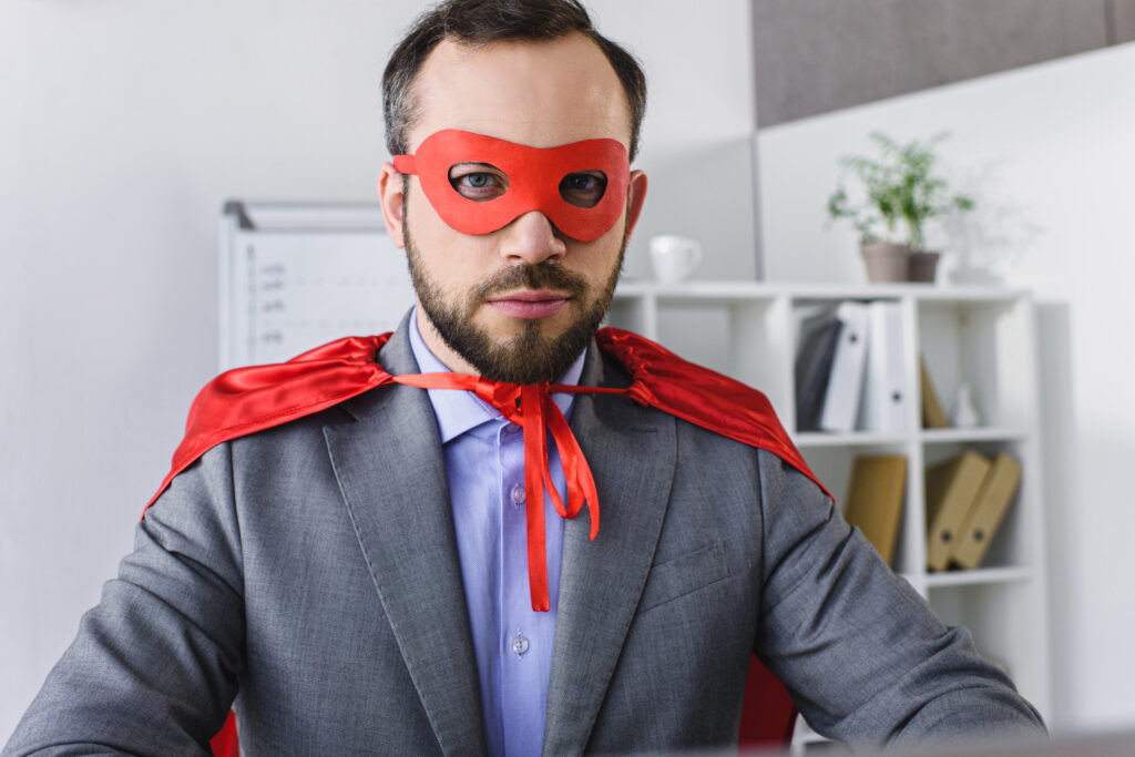 portrait of super businessman in mask and cape looking at camera in office