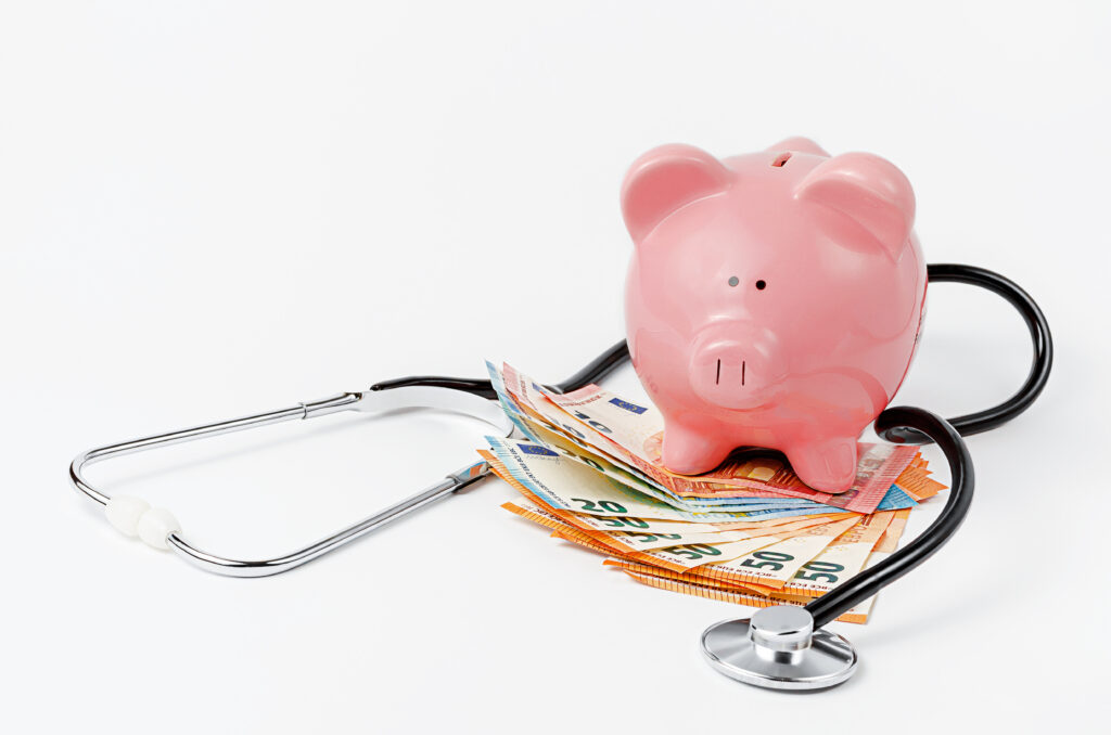 Stethoscope, piggy bank and euro currency on white background.